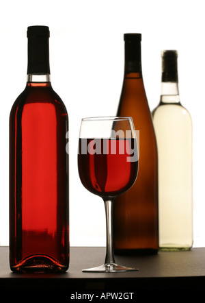 Glas gefüllt mit Rotwein mit Vielzahl von Weinflaschen im Hintergrund und Vordergrund Stockfoto