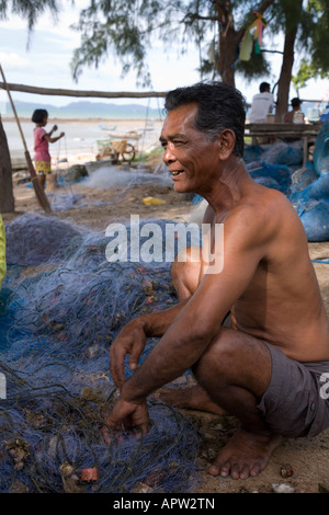 Thailändischer Fischer, der in Netzen gefangene Krabben entfernt, am Phala Beach bei Rayong, Thailand. Stockfoto