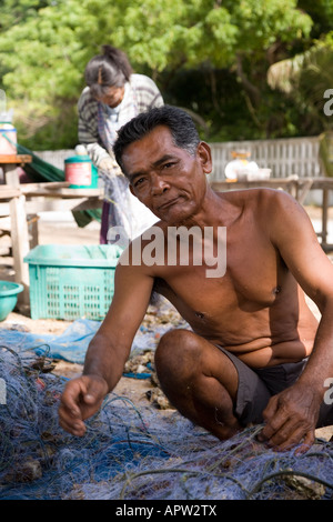 Thailändischer Fischer, der in Netzen gefangene Krabben entfernt, am Phala Beach bei Rayong, Thailand. Stockfoto