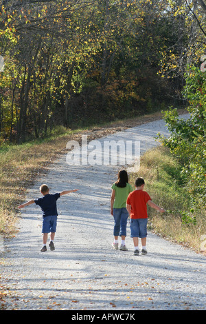 Drei Kinder, die zu Fuß über eine Schotterstraße in Iowa Stockfoto