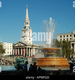 Touristen im berühmten Trafalgar Square Springbrunnen auf der ursprünglichen Höhe und in der Kirche & Turmspitze von St Martins auf den Feldern London England UK Stockfoto