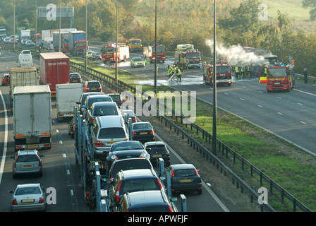 Rauch aus LKW Feuer schließt eine Fahrbahn der Autobahn M25 mit Verkehr langsam hinter die Szene auf der gegenüberliegenden Fahrbahn Stockfoto