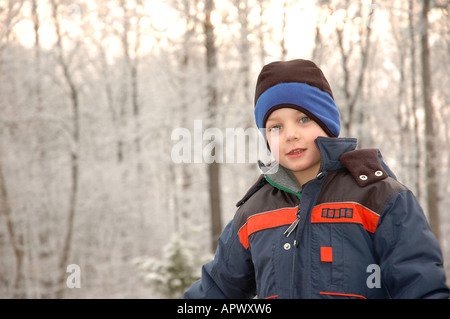 Five-Year-Old Boy, für einen Spaziergang an einem kalten Wintertag nimmt sich eine Auszeit vor der Bäume bei Sonnenaufgang Stockfoto