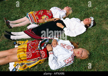 Junge Frauen in traditionellen Kostümen, Sonnenbaden auf der Wiese, traditionelle Feier, Tallinn, Estland Stockfoto