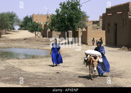 Tuareg-Männer zu Fuß entlang einer Straße in Timbuktu führt einen Esel tragen eine Last von Getreide Stockfoto