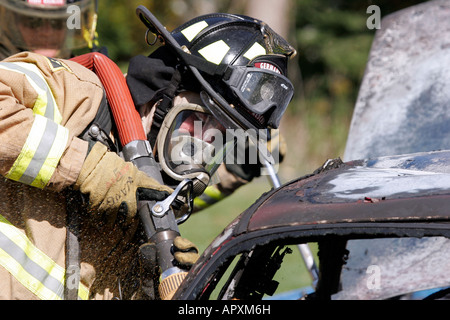 Zwei Germantown Wisconsin Feuerwehrleute setzen ein Auto Feuer bei einem Notfall Feuer-Szene mit einem Neuanschluß Stockfoto