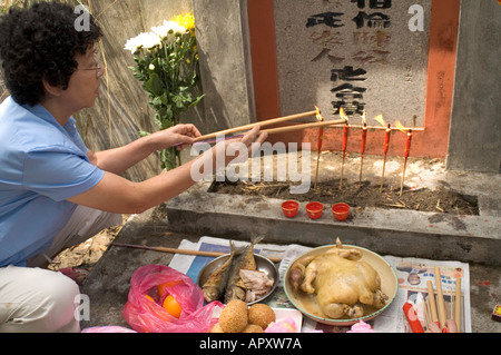 Angebote und Aufleuchten des Josticks auf einem Grabstein während Qing Ming in Malaysia, Süd-Ost-Asien Stockfoto