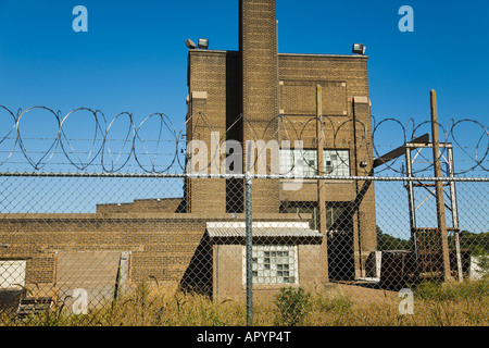 ILLINOIS Moline Spulen aus Stacheldraht über Metall-Kette Link Zaun Sylvan Island Park alte Backsteingebäude, das ehemalige Fabrik Stockfoto