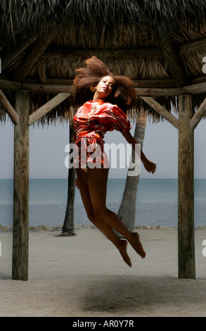 Junge Frau schwebt in der Luft am Strand. Stockfoto