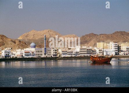 Ein Holzboot ist im Meer mit einer Stadt vor dem Hintergrund gesehen. Stockfoto