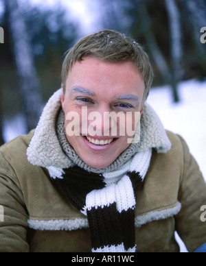 sitzen Sie Outdoor-Tag Winter Baum Bäume Snowpark Nahaufnahme Mann 25 30 junge Blondine Lächeln Lächeln auf den Lippen Make-up Frost Augenbraue Augenbrauen Narbe Stockfoto