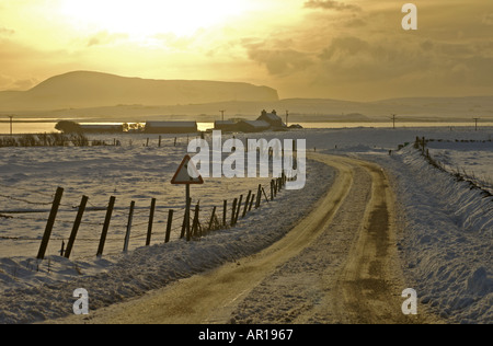 dh Loch of Harray HARRAY ORKNEY Bronze verschneite Felder in der Dämmerung Und Haus Loch Harray und Stenness Hoy Hills abgelegenen Winter Schnee ländliche Straße schottland großbritannien Stockfoto