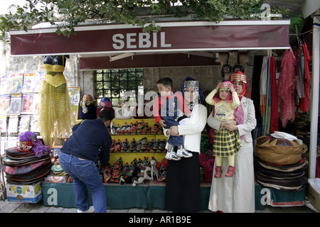 zwei türkische Frauen mit traditionellen Dekorationen auf den Kopf mit zwei Kindern vor Straße für Souvenirs Stall in Istanbul Stockfoto