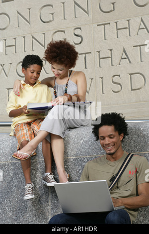 afroamerikanische Familie unterhaltsam, Mutter und Sohn, junge Lesebuch und Vater auf laptop Stockfoto