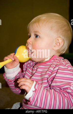 Vertikale Porträt von einem hübschen kaukasischen Babymädchen singen und spielen die Maracas auf eine Musik-Klasse für Kleinkinder Stockfoto