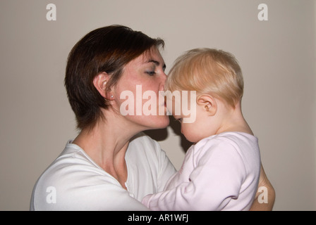 Horizontale Nahaufnahme Portrait einer jungen kaukasischen Mutter gab ihrer Tochter einen Kuss auf die Stirn Stockfoto