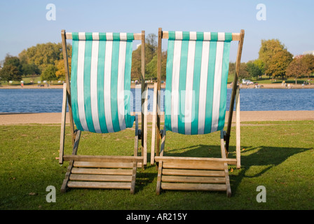 Horizontal dicht gestreift von zwei grünen und weißen hölzernen Liegestühle am See an einem sonnigen Tag Stockfoto