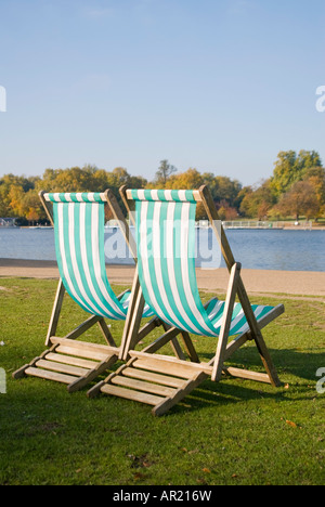 Vertikal nah gestreift zwei grünen und weißen hölzernen Liegestühle am See an einem sonnigen Tag Stockfoto