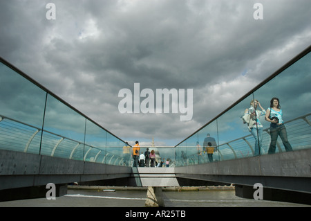 Menschen, die zu Fuß über die Millennium Bridge mit St. Pauls Kathedrale in der Ferne, London, England, UK Stockfoto