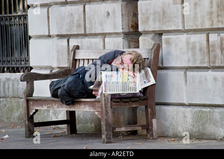 Obdachloser schläft auf Bank außerhalb St. Bartholomews Hospital London Stockfoto