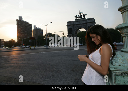 Hispanic Frau stützte sich auf eine Steinfigur im freien Stockfoto