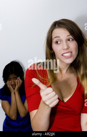 zwei junge Frauen, ein skeptisch, wenn Daumen nach oben oder unten, während die andere steht enttäuscht hinter Stockfoto