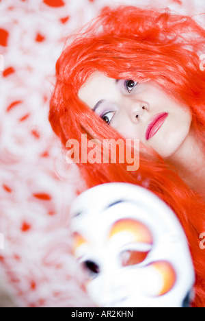 herrsche eine Frau mit einer roten Perücke und Karneval Maske Stockfoto