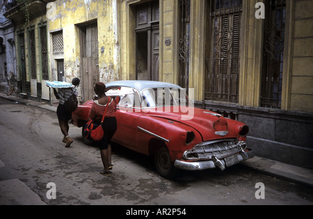 Einheimische Frauen tragen Kuchen vorbei an alten 50er Jahre Auto, Alt-Havanna, Kuba. Stockfoto