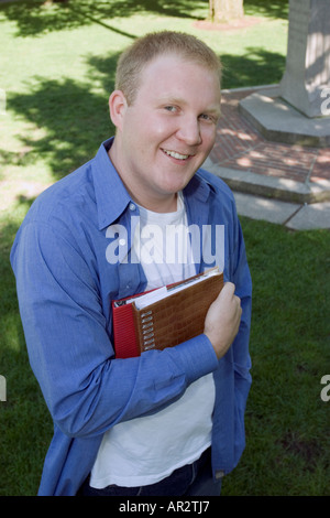 Mann, draußen, blickte in die Kamera hielt Bücher unter dem arm Stockfoto
