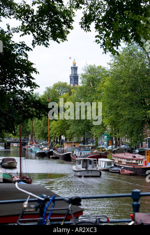 HOLLAND AMSTERDAM CANAL MIT BÄUMEN UND WESTERTOREN WEST TOWER KIRCHE SPIRE MIT NIEDERLÄNDISCHEN NATIONALFLAGGE Stockfoto