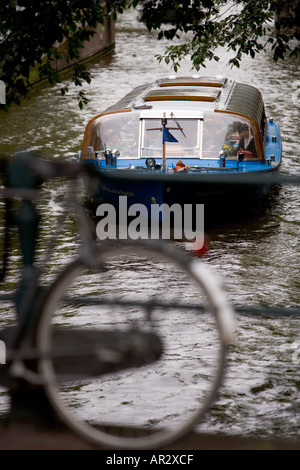 HOLLAND AMSTERDAM TOURENBOOT REISEN AUF EIN KANAL DURCH EIN FAHRRAD ANGEKETTET AN EINER BRÜCKE GESEHEN Stockfoto