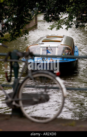 HOLLAND AMSTERDAM TOURENBOOT REISEN AUF EIN KANAL DURCH EIN FAHRRAD ANGEKETTET AN EINER BRÜCKE GESEHEN Stockfoto