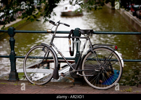 HOLLAND AMSTERDAM TOURENBOOT REISEN AUF EIN KANAL DURCH EIN FAHRRAD ANGEKETTET AN EINER BRÜCKE GESEHEN Stockfoto