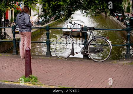 HOLLAND AMSTERDAM TOURENBOOT REISEN AUF EINEM KANAL DURCH EIN FAHRRAD ANGEKETTET AN EINER BRÜCKE MIT BLICK AUF EINE KARTE GESEHEN Stockfoto