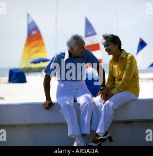 Älteres Ehepaar im Ruhestand genießen einen Chat an einem sonnigen Tag am Strand in einem warmen Klima Stockfoto