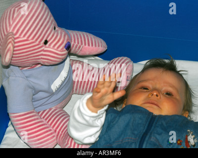 10 Monate altes Baby Mädchen in Schlafsack mit rosa Stripey Teddybär Stockfoto