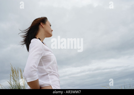 Junge Frau trägt weißes Hemd, bewölkten Himmel aufzublicken Stockfoto