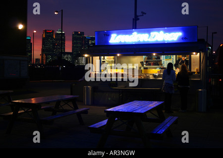 London-Diner dienen außerhalb der Hütte an der North Greenwich Station, London mit Canary Wharf im Hintergrund Stockfoto