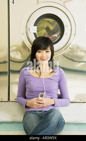 Asiatische Frau anhören von MP3-Player im Waschsalon Stockfoto