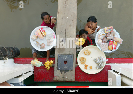 Mit Snacks für Passagiere, Vogelauge Ansicht von Boot von Frauen stehen hüfthoch im Fluss mit Tabletts von Lebensmitteln, Obst auf th Stockfoto