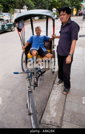 Trishaw-Fahrer/Rikscha-Fahrer entspannt sich und spricht mit einem thailändischen Fußgänger in Chiang Rai, Thailand. Stockfoto