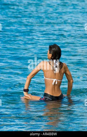 Eine hawaiianische Frau schwebt auf ihrem Board warten auf einen anderen Satz von Wellen auf Waikiki Beach zu gelangen. Stockfoto