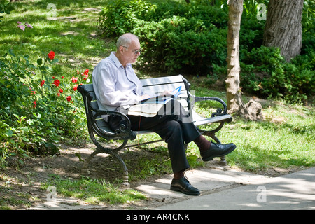 Mann auf einer Parkbank liest Stockfoto