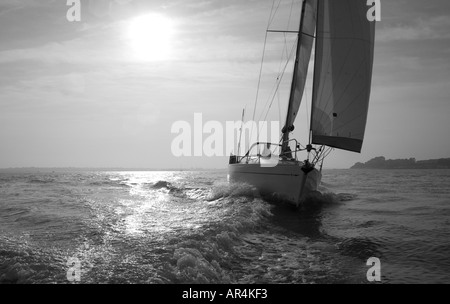 schwarz / weißes Bild aus Blick über das Meer mit einem Boot Segeln im Wasser die Sonne strahlt nach unten Stockfoto