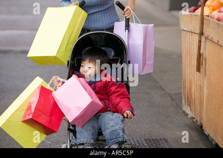 Junge im Kinderwagen mit Einkaufstüten Stockfoto