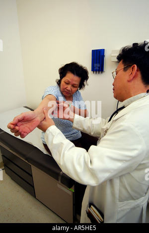 Ein Arzt untersucht einen mittleren Alters Patienten an einer vietnamesisch-amerikanische Gemeinschaft medizinische Klinik, Garden Grove, Kalifornien, USA. Stockfoto