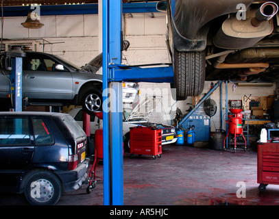Ein Fahrzeug wird auf einem hydraulischen Autokran in einer geschäftigen Autowerkstatt im Industriepark von Holon, Israel, gehoben Stockfoto