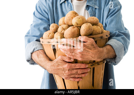 Mann-Betrieb-Korb mit Kartoffeln Stockfoto