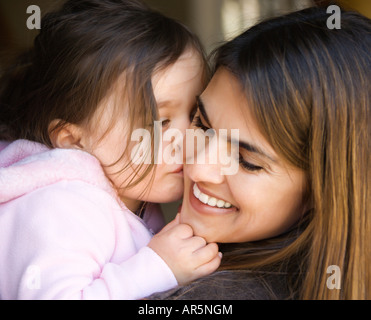 Kaukasische Mutter Holding Tochter ihre Wange küssen und lächelnd Stockfoto