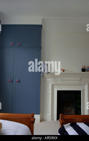 Blauen Schrank und traditionellen weißen Kamin in modernen weiße Schlafzimmer Stockfoto